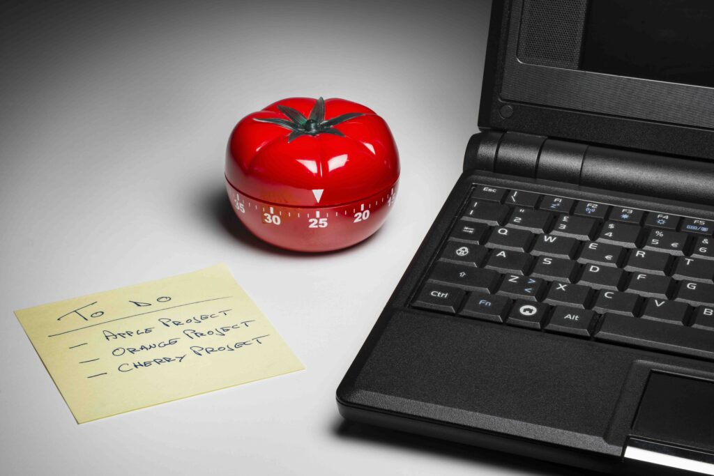 Bild von einem Laptop und einer Küchenuhr in Tomatenform