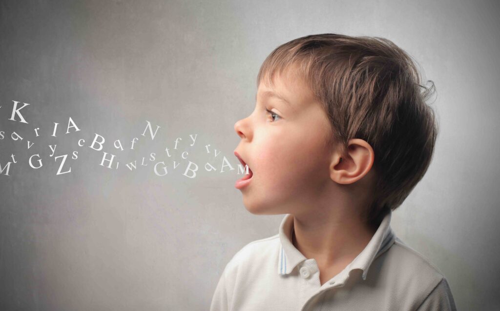 Junge mit Sprechblase mit Buchstaben des Alphabets