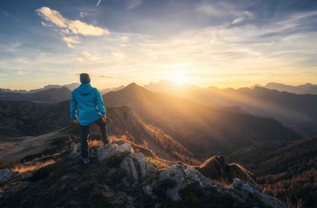 Bergsteiger auf dem Gipfel blickt auf den Sonnenaufgang über der Bergkette