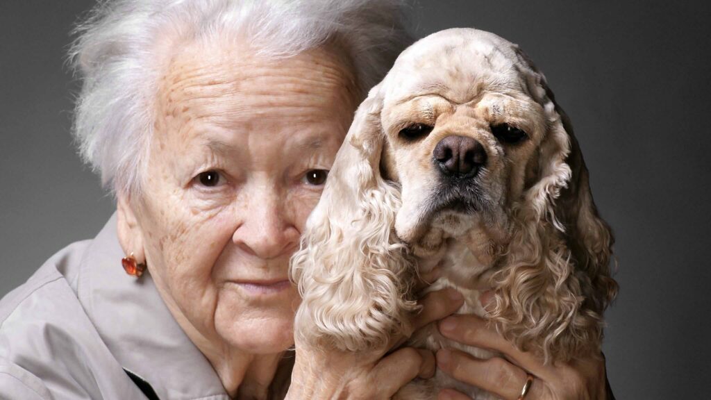 ältere Dame mit Hund im Arm