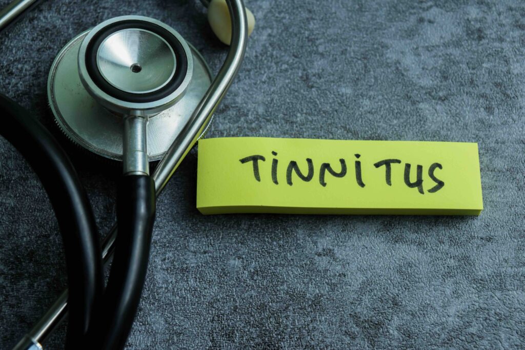 Concept of Tinnitus write on sticky notes with stethoscope isolated on Wooden Table.