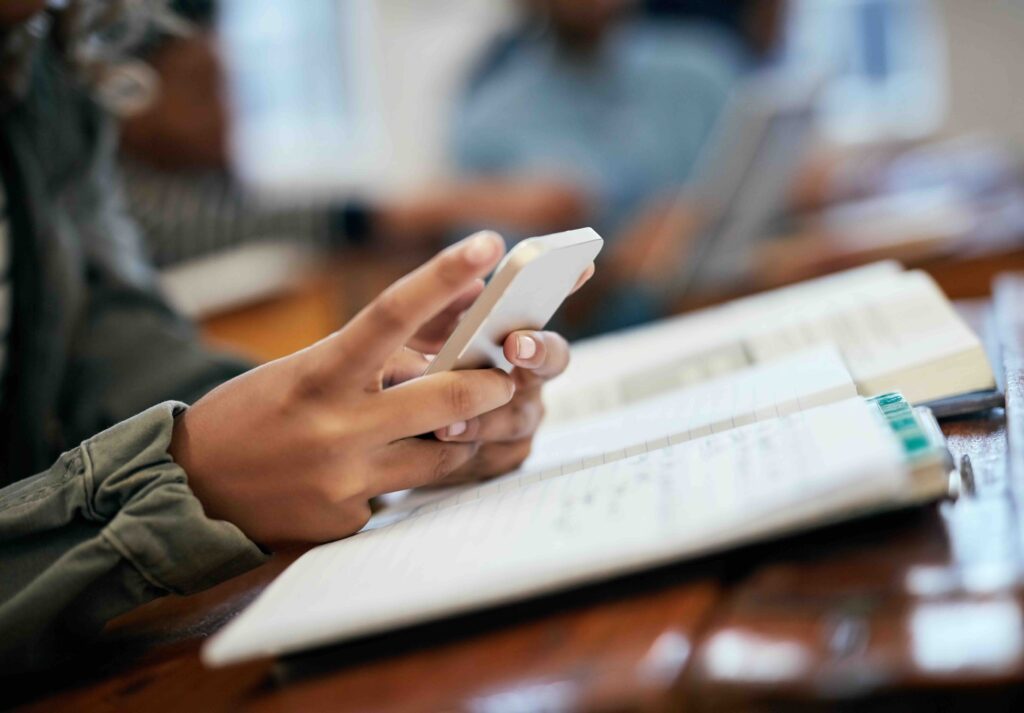 Hands, school and university with phone for research, reading message on mobile app in classroom. Student, college or social media with education or learning, scroll for news story with technology