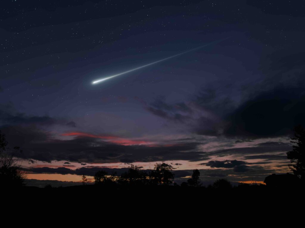 Night landscape with a meteor flash. A bright fireball in the sky above the clouds.
