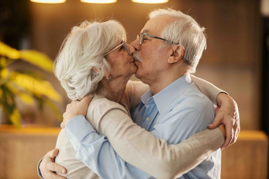 Affectionate senior couple in love standing at home, hugging and kissing.