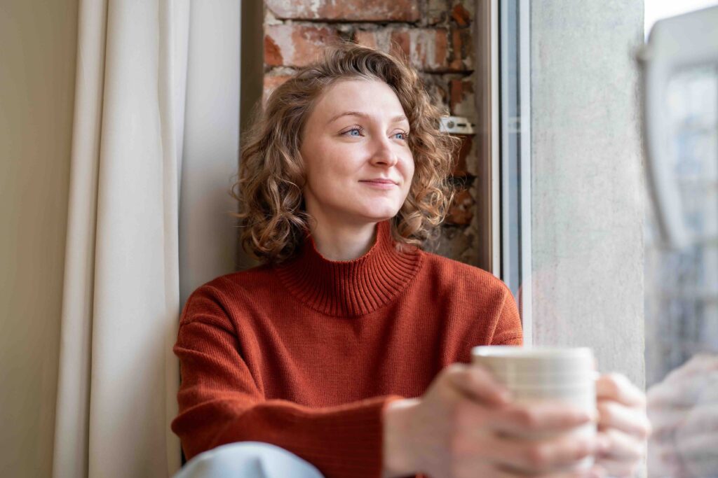 Happy relaxed woman enjoying quiet time simple joys holding coffee mug, lost in positive thoughts. Serene female feels deep inner peace, self-reflection tranquil mood. Calmness, gratitude, contentment