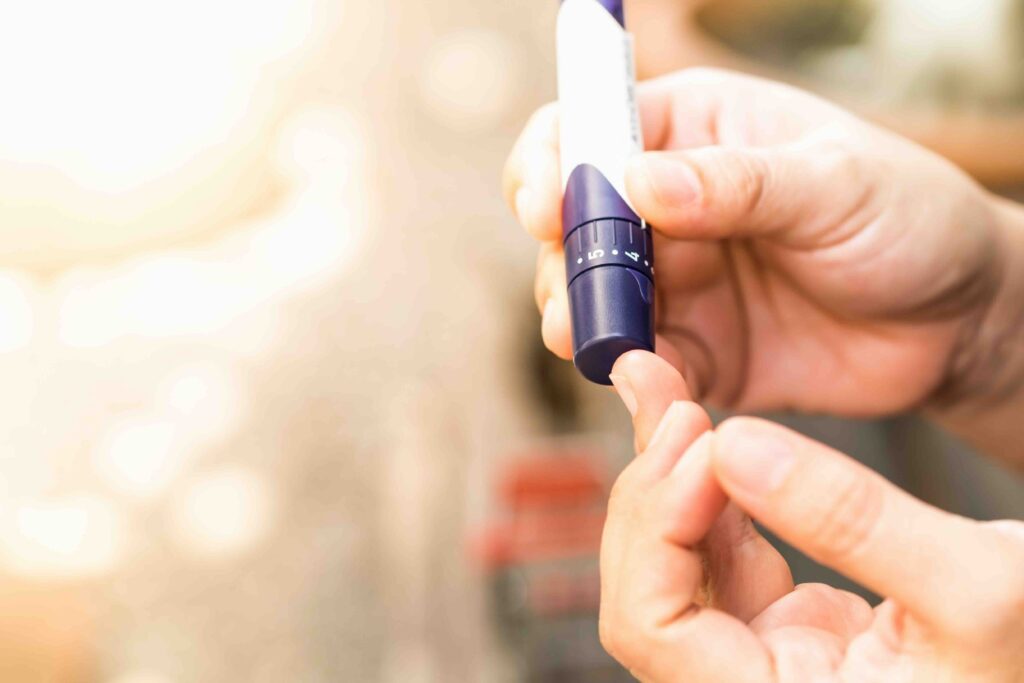 Close up of woman hands using lancet on finger to check blood sugar level by Glucose meter using as Medicine, diabetes, glycemia, health care and people concept.