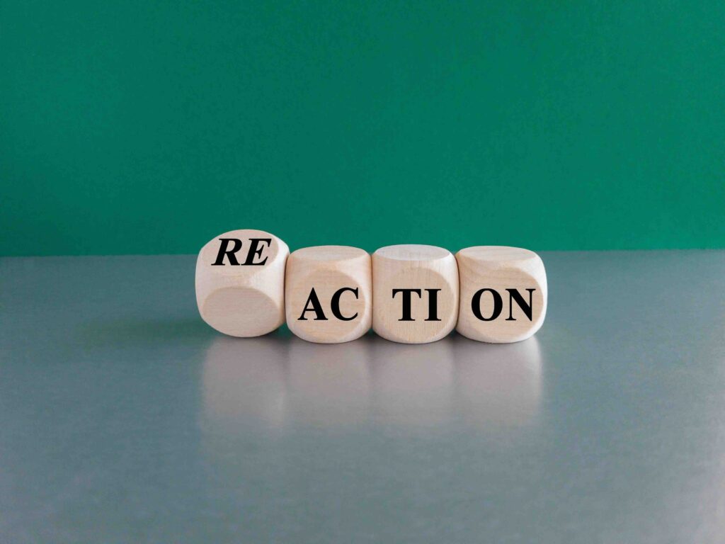 Action and reaction symbol. Turned a cube and changes the word action to reaction. Beautiful green background, grey table, copy space. Business and action to reaction concept.