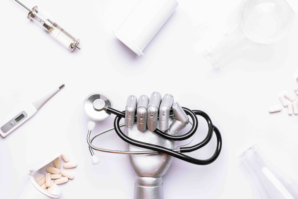Silver metallic robot hand with medical stethoscope on white backgroond with medical equipment and pills top view. AI and smart technologies in medicine, researches and diagnostic concept.