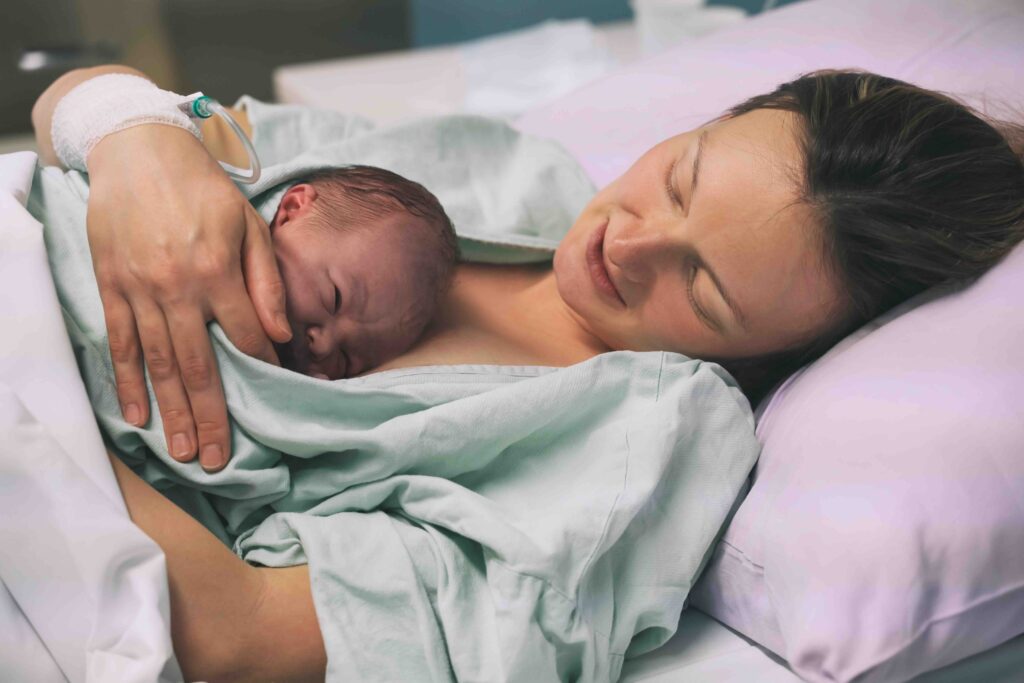 Mother and newborn. Child birth in maternity hospital. Young mom hugging her newborn baby after delivery. Woman giving birth. First moments of baby life after labor.