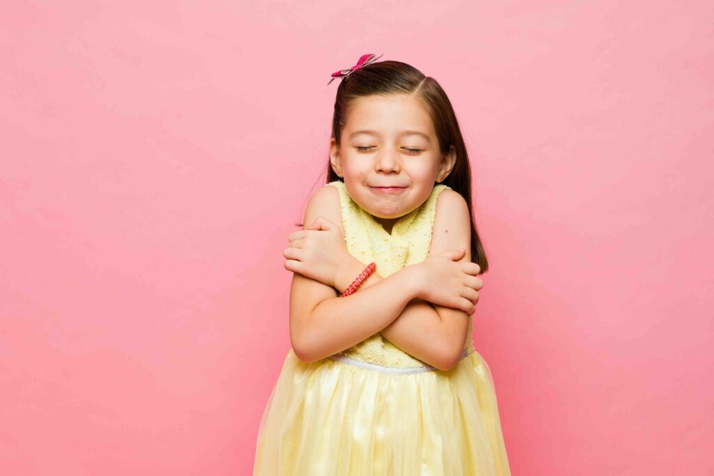Cold cute little girl wearing a summer dress having chills and shivering looking upset next to a pink copy space